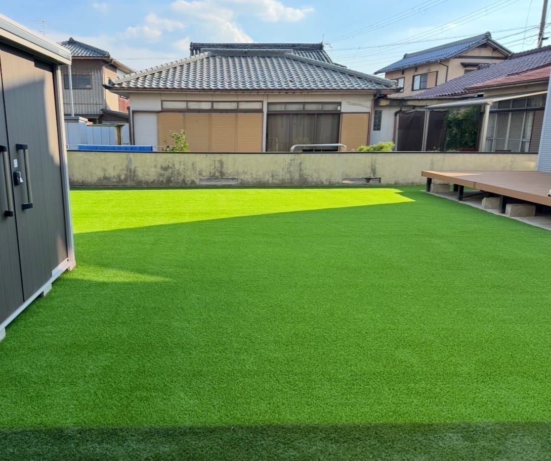 野洲市で施工した人工芝の広い庭。物置とウッドデッキに挟まれた芝生