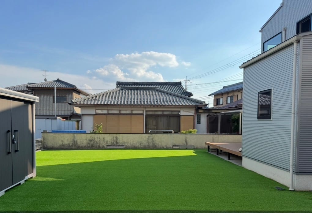 野洲市H様邸の施工後。物置とウッドデッキに挟まれた広い庭一面に張られた人工芝